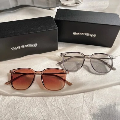 Two pairs of glasses on a white cloth, one with brown tinted lenses and one with clear lenses, beside their black cases