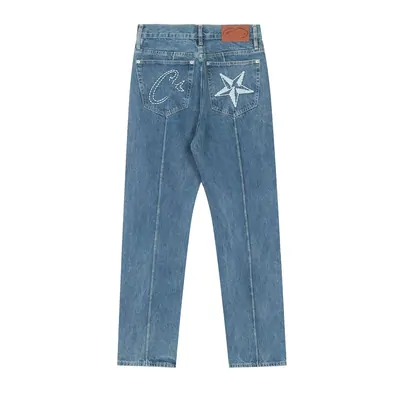 A pair of mid blue jeans photographed flat on white, with an embroidered star motif on the back pocket